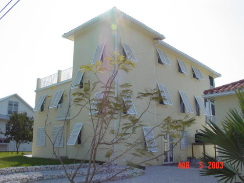Image showing a multi-story, yellow home with white Bahama hurricane shutters over the windows