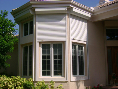 White rolling shutters installed on the front windows of a home in Southwest Florida
