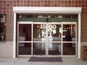 White, roll down shutters installed over entry doors on a brick commercial building