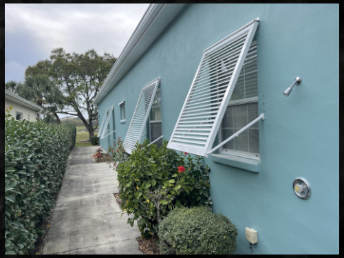 white bermuda shutters installed on blue home in englewood fl