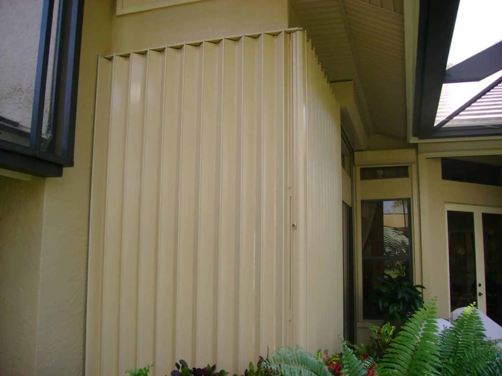 Tan Eurex Shutters PTX™ Accordion Shutters installed on a tan home in florida