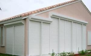 White roll down shutters on a peach home
