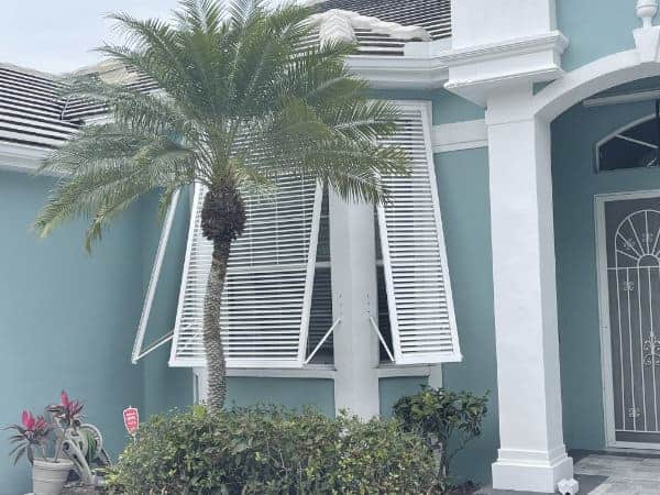 White hurricane shutters on a blue home.