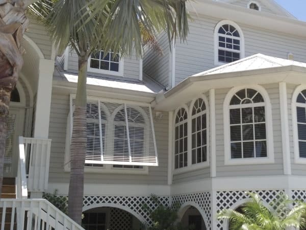 White bahama shutters go perfectly on this tan beach home.