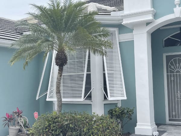 White bahama shutters on a blue green home in Englewood FL.