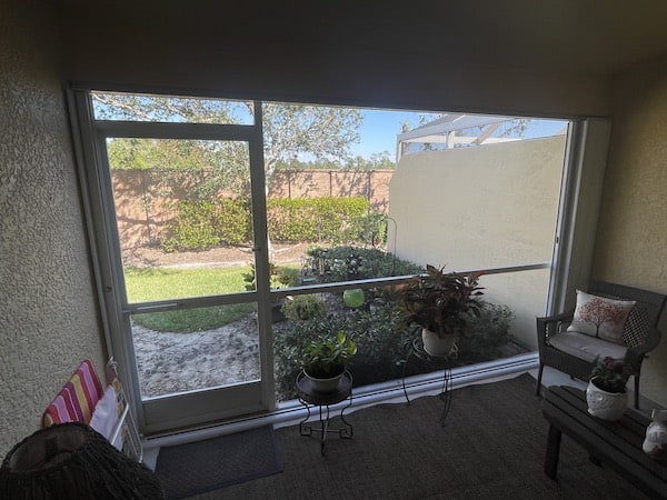 White accordion shutters shown in the open position from the inside of a lanai