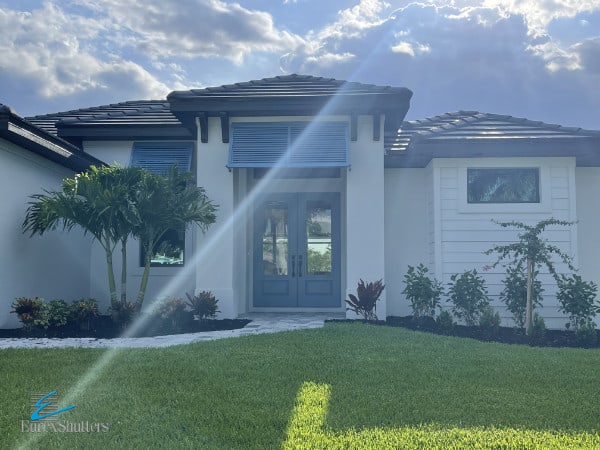 Blue deco Bahama shutters shown over an entry way on a home in Cape Coral Florida.
