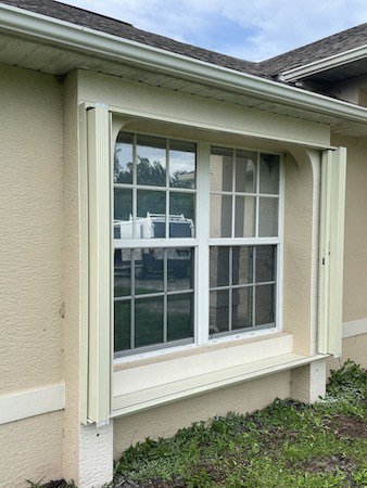 Ivory accordion shutters on a tan home in Southwest Florida
