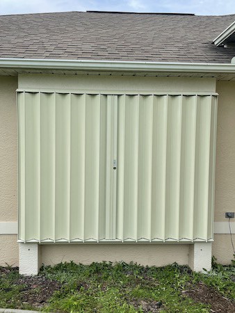 Ivory accordion shutters on a tan home in Southwest Florida
