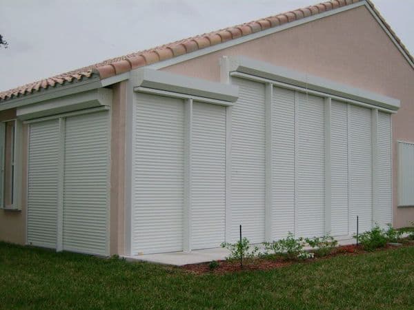 Tan house with white shutters. Specific shutters shown are again white roll down shutters.