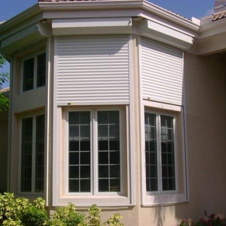 Tan home with white roll shutters