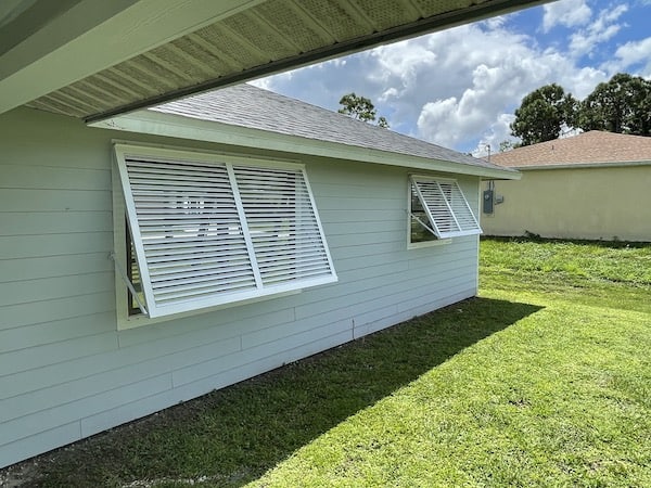White bahama shutters on grey home.