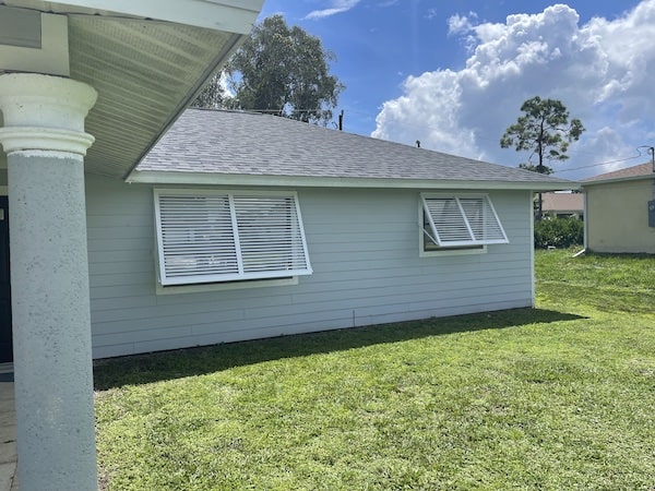 White bahama hurricane shutters on grey home.