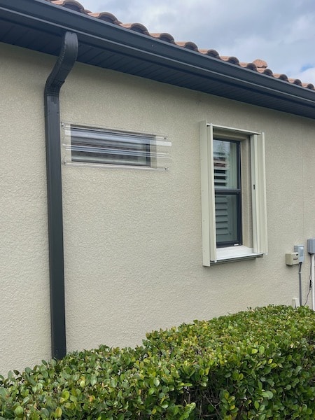 Beige Eurex Shutters PTX Accordion Shutters on small window of a beige house in the open position.