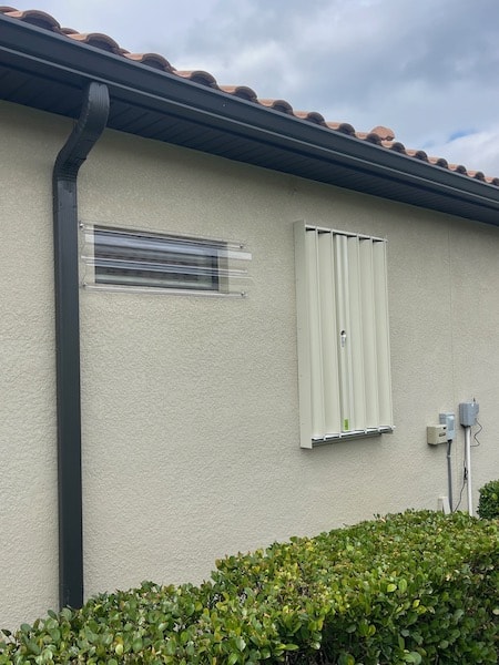 Beige Eurex Shutters PTX Accordions on small window of a beige house in the closed position.