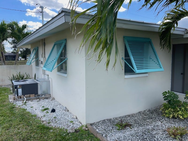 Custom Eurex Shutters PTX Bahama Shutters in custom tiffany blue color shown on the side of a home in Lehigh Acres FL