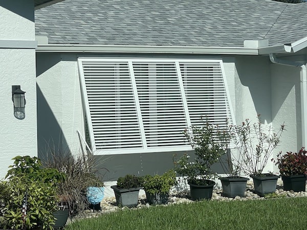 Aluminum hurricane shutters shown as a wide Bahama shutter on a window