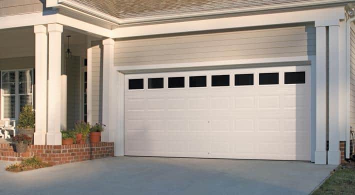White hurricane proof garage door on a home, double garage door width, with eight impact glass windows.