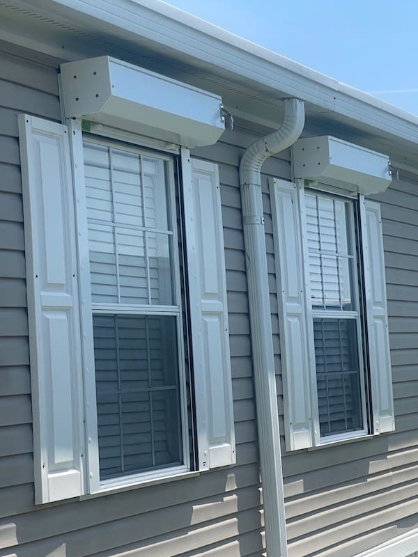 rolldown shutters installed on two single windows. White slats, white tracks and white housing box