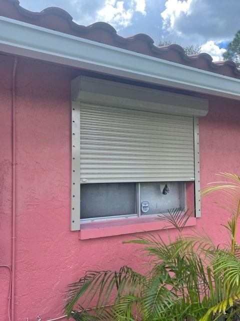 Beige rolldowns shown in a partially open position on a window. Beige slats, beige tracks and beige housing box
