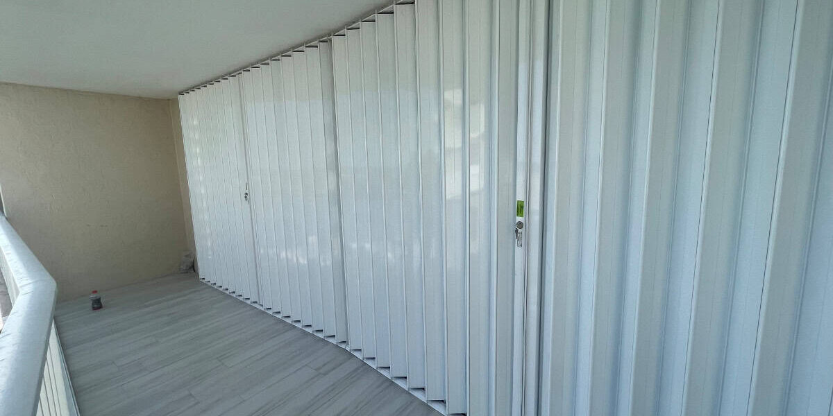 White Accordion shutters covering the glass of a balcony in Marco Island Florida