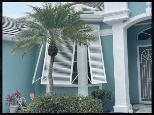 Three, white, full-view, Bahama shutter installed on the front of a home. In Englewood Florida.