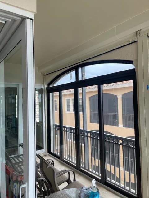 Bronze, aluminum impact sliders with bronze, aluminum impact windows above the doors