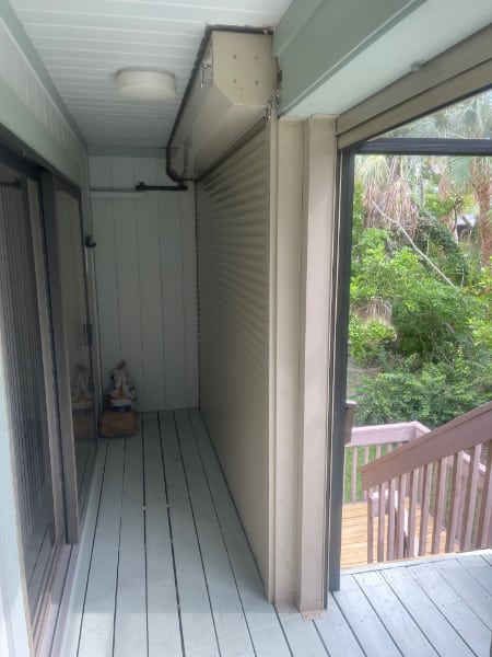 Beige roll-down shutters shown in the fully closed position on the back porch of a home in Sanibel Florida.