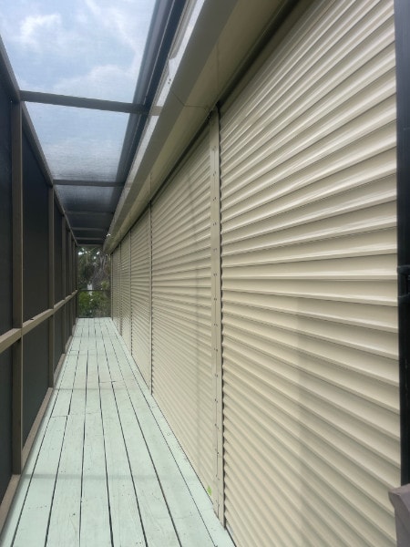 Closed rolling shutters installed across the width of a screened in porch and lanai in Sanibel Florida.