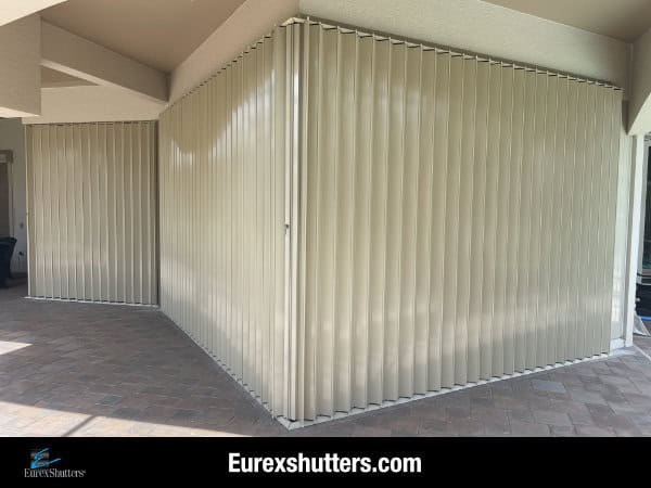 Beige accordion shutters shown closed on the patio of a beige condo unit in Fort Myers Florida