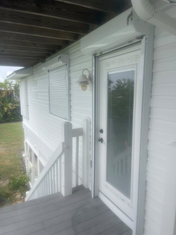 A home in Bokeelia Florida with a combination of white hurricane shutters installed. Products include white accordion shutters, white manual roll down shutters and white automatic roll down shutters.