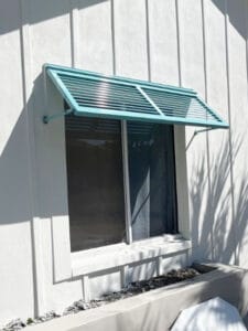 Half Bahama shutter in a custom blue color installed on a window of a home.
