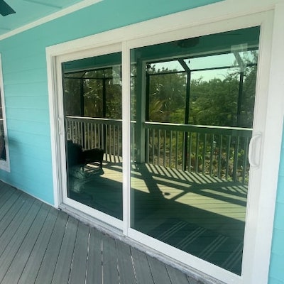 White, vinyl, mpact sliding glass door installed on a green home's patio.