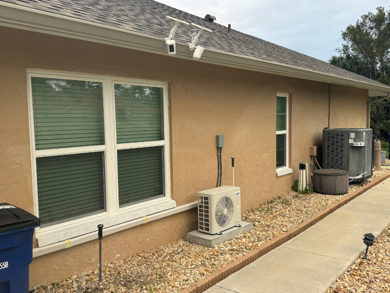Tree double hung impact windows with white vinyl frames on a beige home.