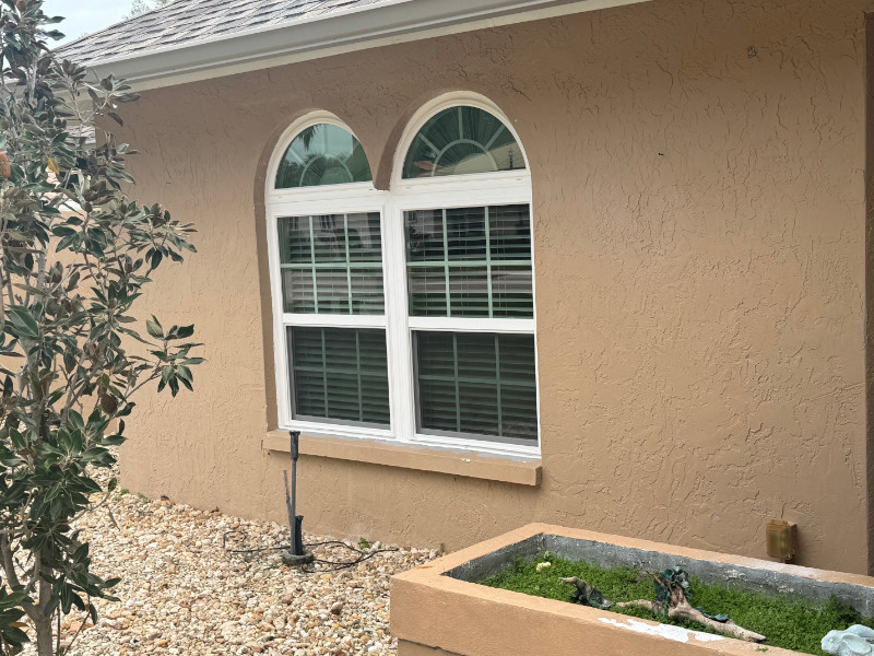 Two double hung impact windows with white vinyl frames and half circle window toppers.