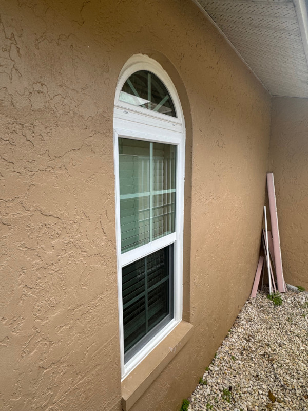 A white vinyl framed double hung impact window with an arched impact window above.