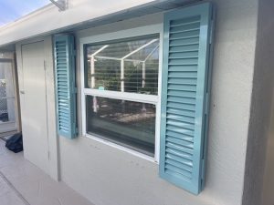 Blue Colonial shutters on a window of a beige house