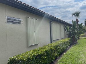 Beige accordion shutters closed over windows on a home