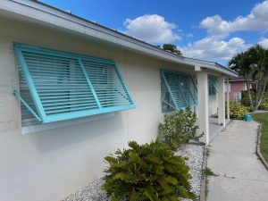 Custom blue Bahama shutters installed on a home