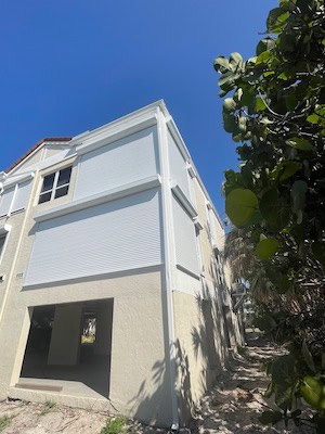 Tan house with white shutters (roll shutters).