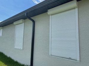 White accordion shutters closed over windows on a home