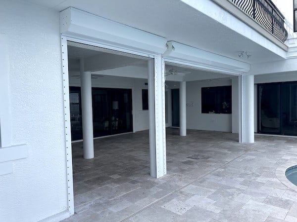 White automatic roll down shutters installed on the lanai openings of a white home in Cape Coral Florida
