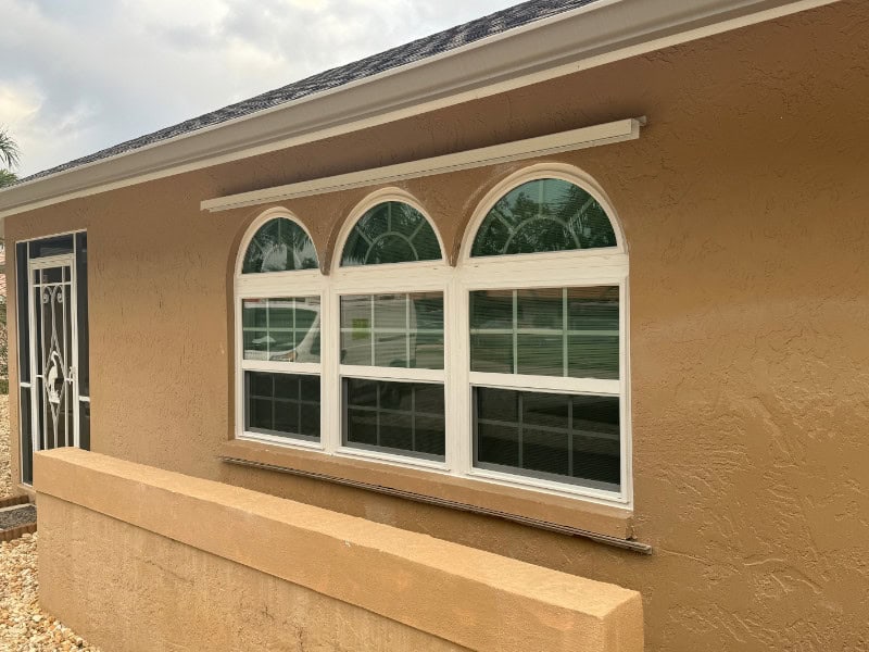White impact rated windows installed on a beige home in Fort Myers Florida.