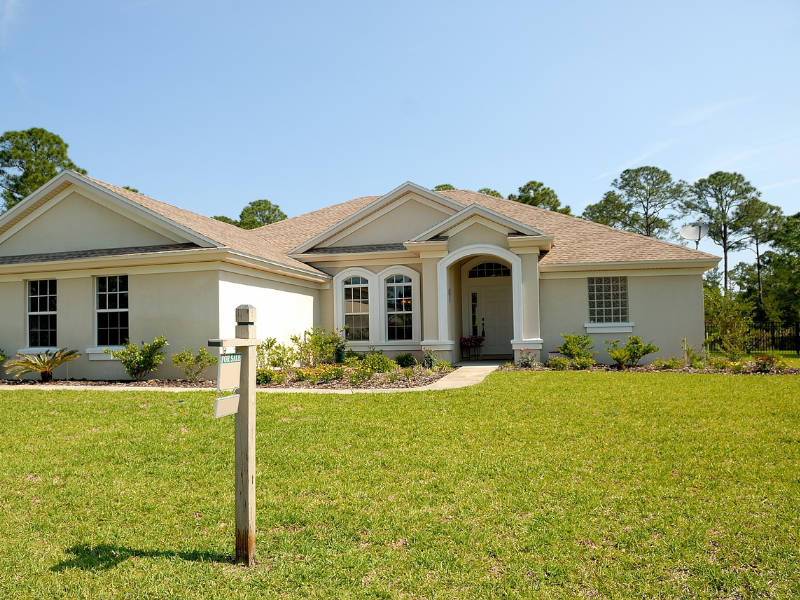 Single story, tan ranch home with a tan roof and impact windows.