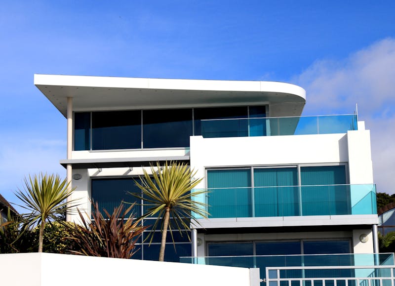 Modern home with concrete walls, large glass panels, and flat roof line.