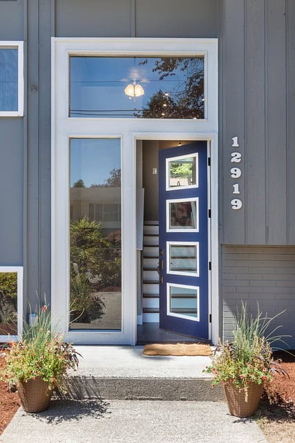 Home with a blue front door with glass inserts and wide sidelight.