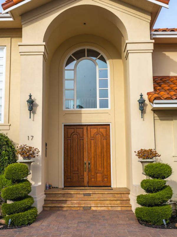 Mediterranean style home with grand entrance and arched openings and window and red clay tile roof.
